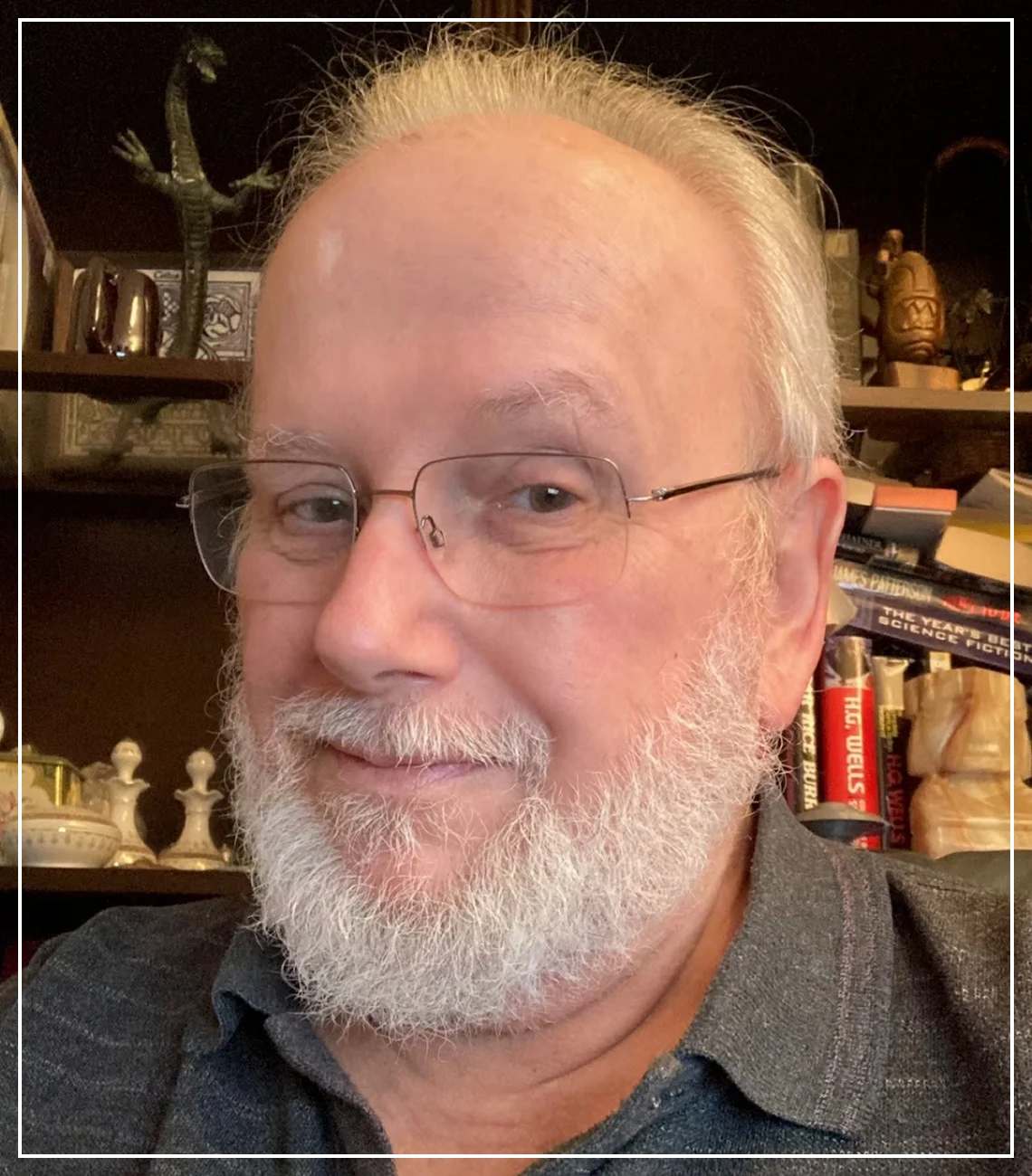 Man with glasses and beard, smiling indoors.