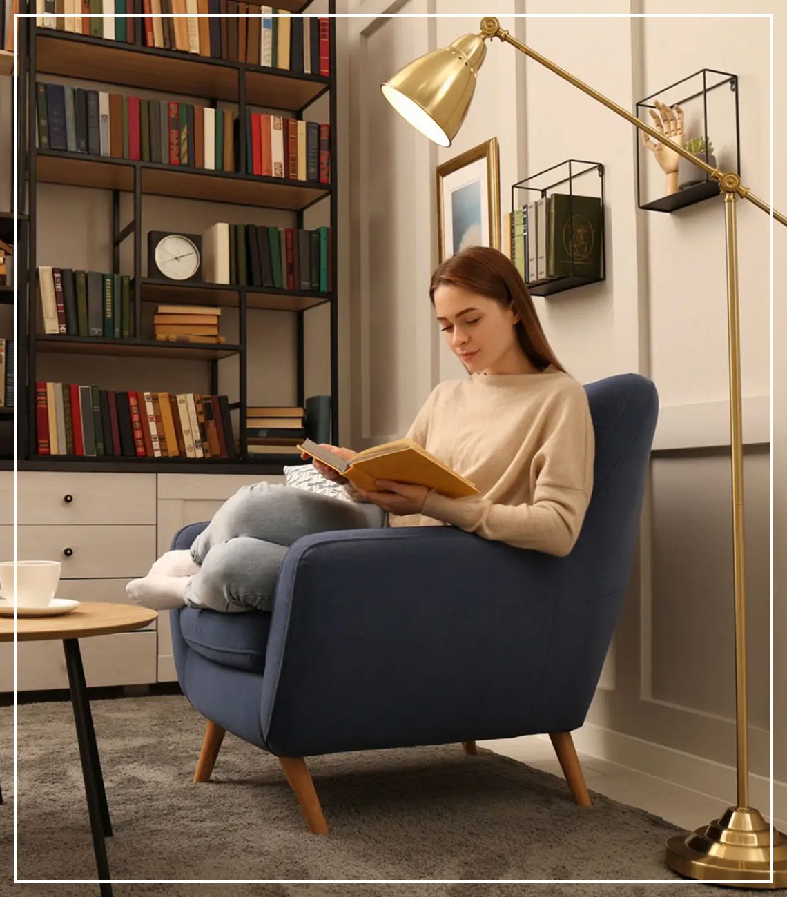 A woman reading a book in a cozy living room with a cat on the chair.