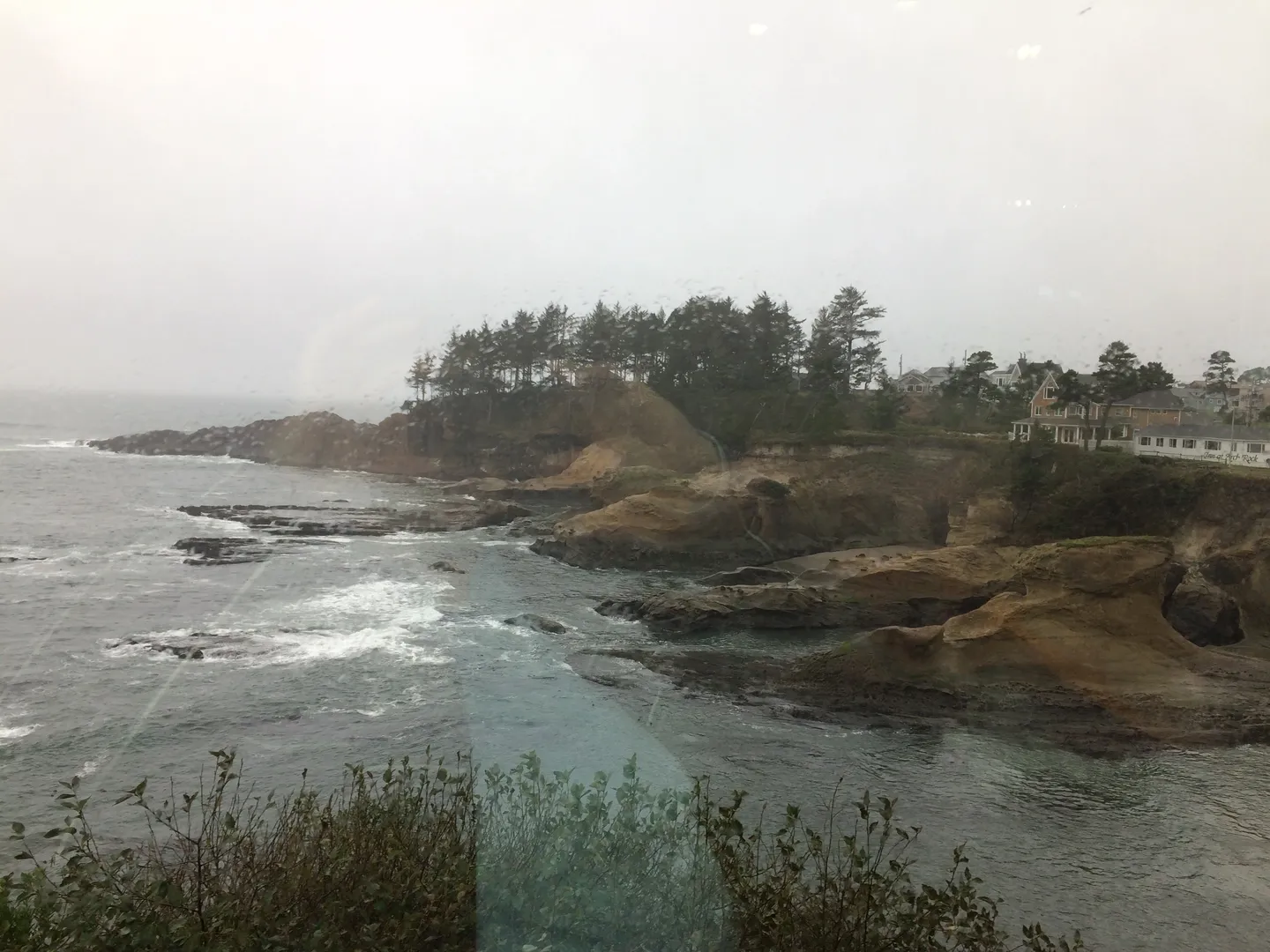 Rocky coastline with waves crashing under cloudy skies.