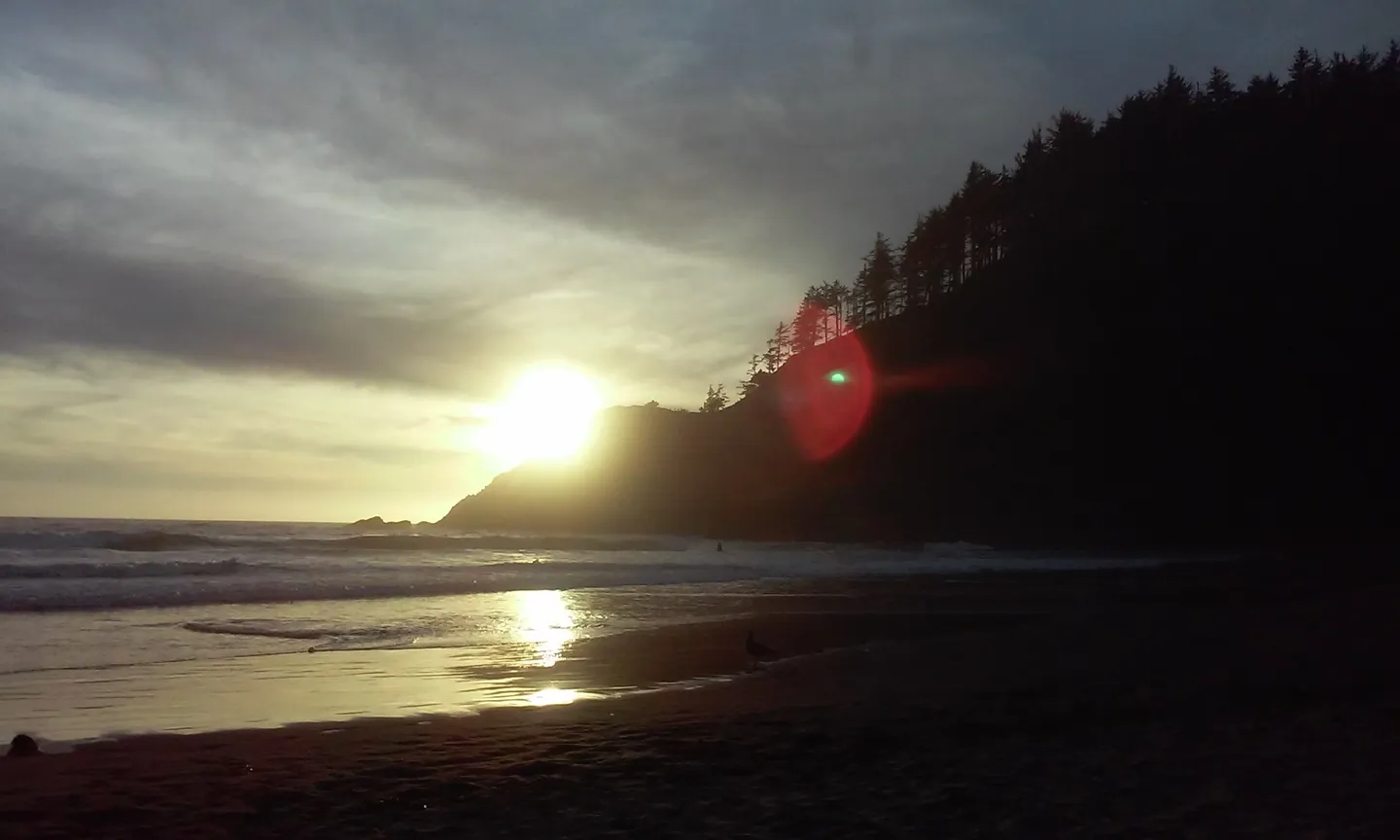 Sunset casting golden light over a beach with cliffs.